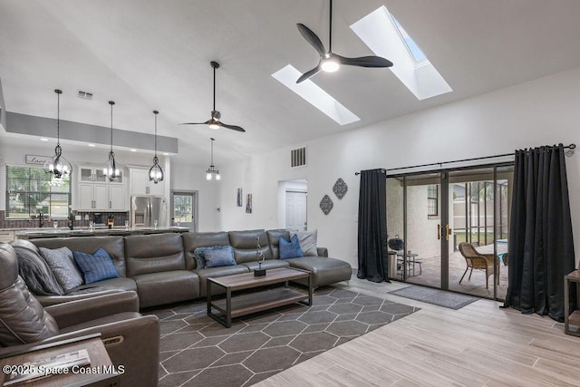 living room featuring ceiling fan with notable chandelier, high vaulted ceiling, and wood-type flooring