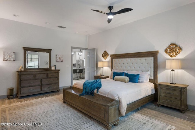 bedroom featuring light hardwood / wood-style flooring, ceiling fan, and stainless steel refrigerator with ice dispenser