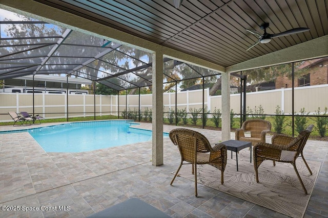 view of swimming pool featuring ceiling fan, glass enclosure, and a patio