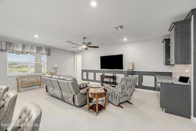 living room with a textured ceiling, visible vents, a ceiling fan, and recessed lighting