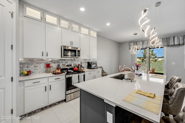 kitchen featuring light tile patterned floors, stainless steel appliances, tasteful backsplash, a kitchen island with sink, and a sink