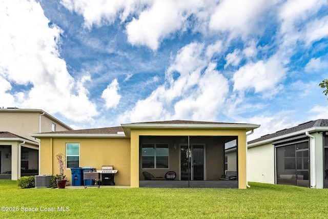 rear view of house with a lawn, cooling unit, a sunroom, and stucco siding