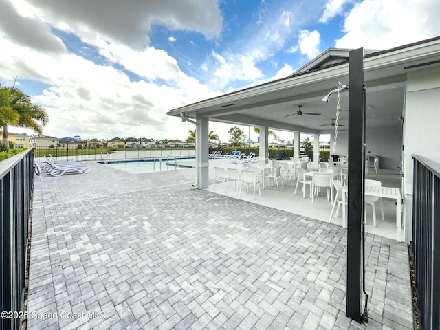 pool with a patio, fence, and a ceiling fan