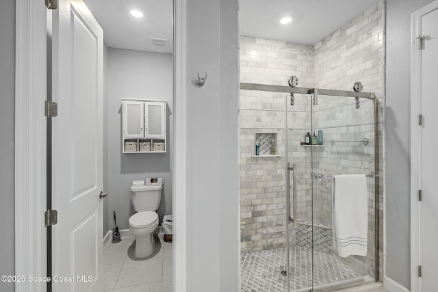 bathroom featuring baseboards, visible vents, toilet, tile patterned flooring, and a shower stall