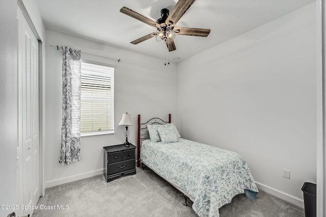 carpeted bedroom with a ceiling fan, a closet, and baseboards