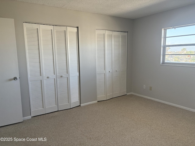 unfurnished bedroom with multiple closets, carpet flooring, and a textured ceiling