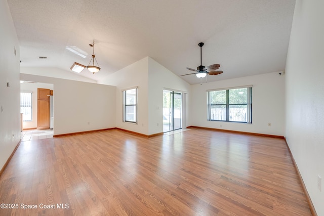 spare room with vaulted ceiling, light wood-type flooring, a ceiling fan, and baseboards