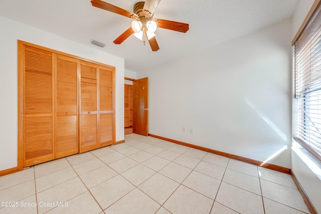 unfurnished bedroom featuring light tile patterned floors, a closet, visible vents, and baseboards