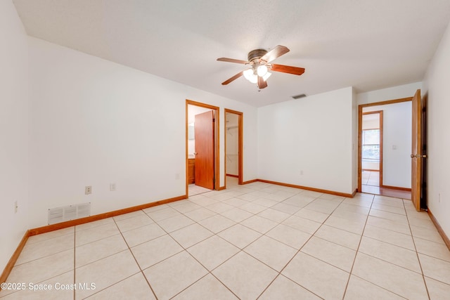 empty room featuring a ceiling fan, visible vents, and baseboards