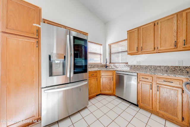 kitchen with lofted ceiling, stainless steel appliances, a sink, and light stone countertops