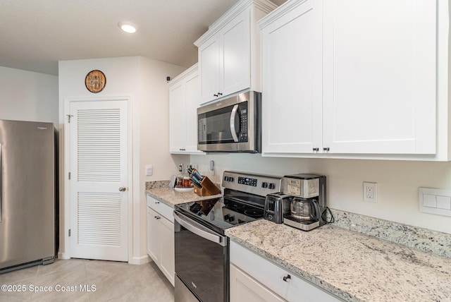 kitchen with light stone counters, stainless steel appliances, light tile patterned floors, and white cabinets