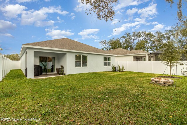 back of house with a yard, a fire pit, and central AC