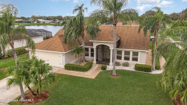 view of front facade featuring stucco siding, a water view, a front yard, a garage, and driveway