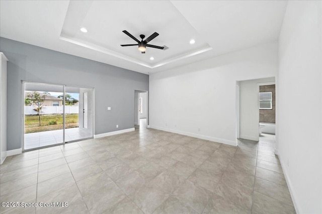 tiled spare room with ceiling fan and a raised ceiling