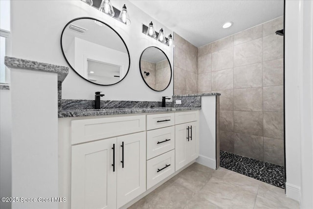 bathroom with vanity, tile patterned flooring, and tiled shower