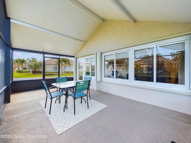 sunroom with lofted ceiling with beams and a healthy amount of sunlight