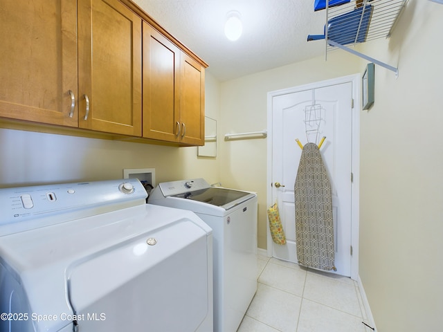 clothes washing area featuring cabinets, washer and dryer, light tile patterned floors, and a textured ceiling