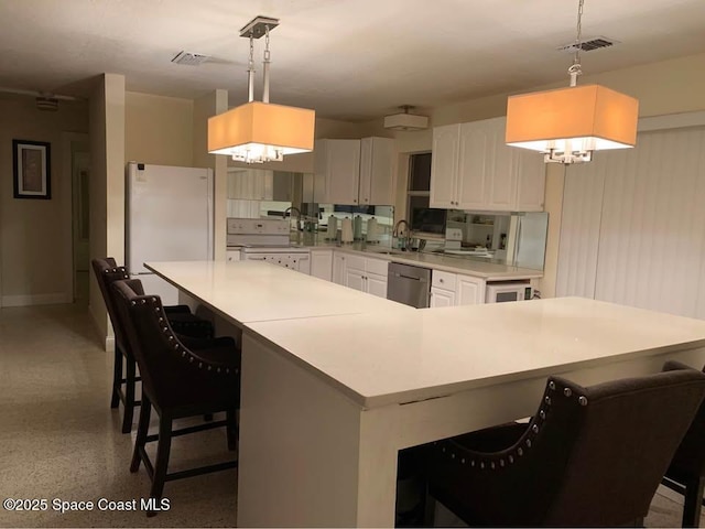 kitchen with a breakfast bar, decorative light fixtures, white appliances, and a spacious island