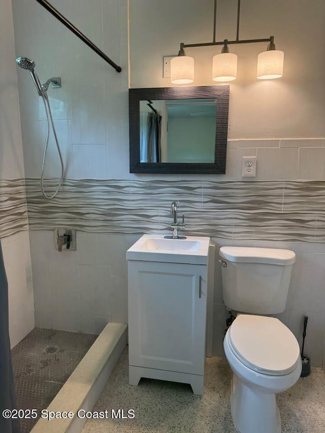 bathroom featuring vanity, toilet, tile walls, and tiled shower