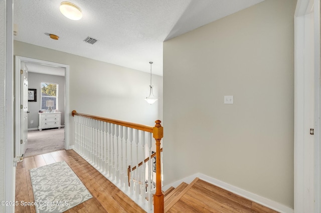 828 Parkwood Ave, Titusville, FL 32796 - hall featuring light wood-style floors, an upstairs landing, baseboards, and a textured ceiling
