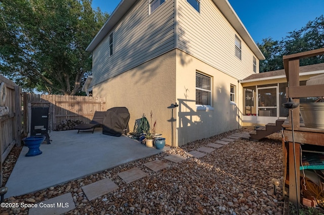 828 Parkwood Ave, Titusville, FL 32796 - view of side of property featuring a sunroom, a patio, stucco siding, and a fenced backyard