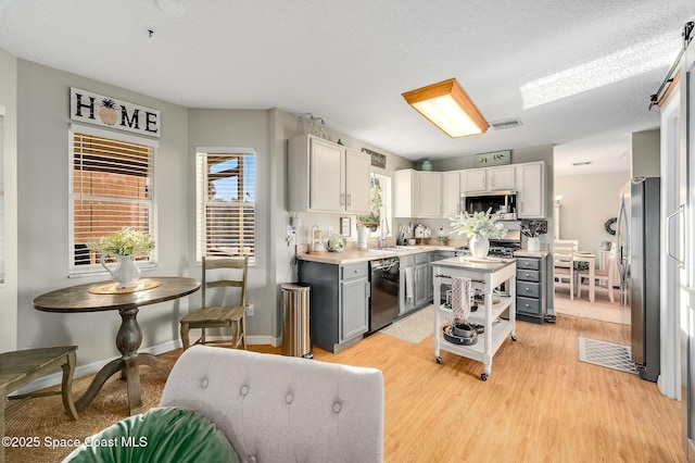 828 Parkwood Ave, Titusville, FL 32796 - kitchen with stainless steel appliances, light countertops, a sink, light wood-type flooring, and white cabinets