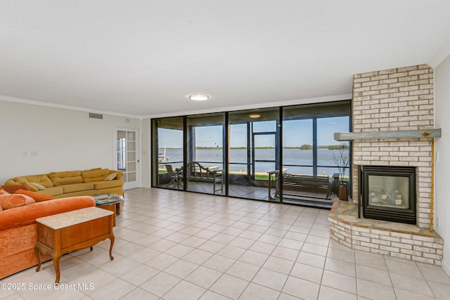 living room featuring light tile patterned floors, a water view, ornamental molding, expansive windows, and a brick fireplace