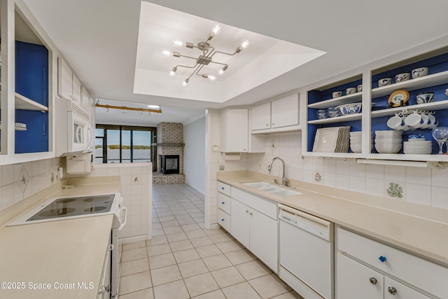 kitchen featuring sink, white cabinetry, a raised ceiling, white appliances, and decorative backsplash