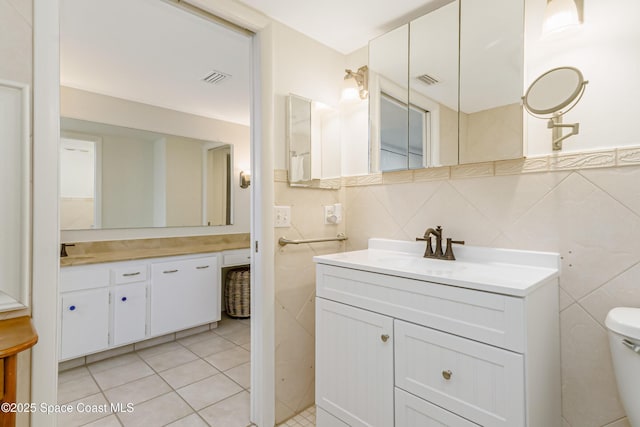 bathroom with tile patterned floors, vanity, toilet, and tile walls