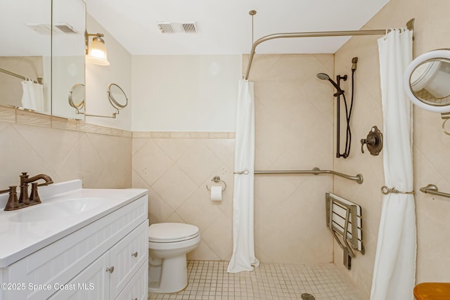 bathroom with tile walls, tile patterned flooring, vanity, toilet, and walk in shower