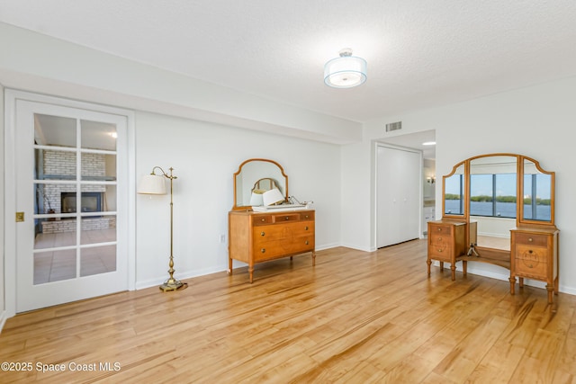 interior space with light hardwood / wood-style flooring, a textured ceiling, and a water view