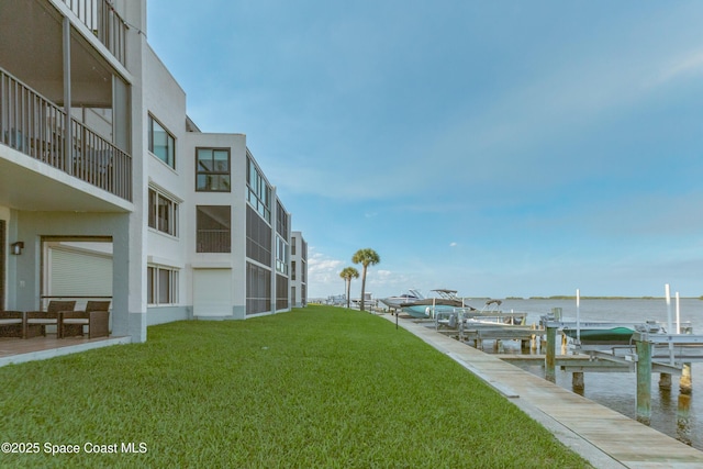 view of dock with a water view and a yard