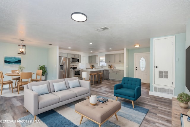 living room with sink, hardwood / wood-style floors, a textured ceiling, and a notable chandelier