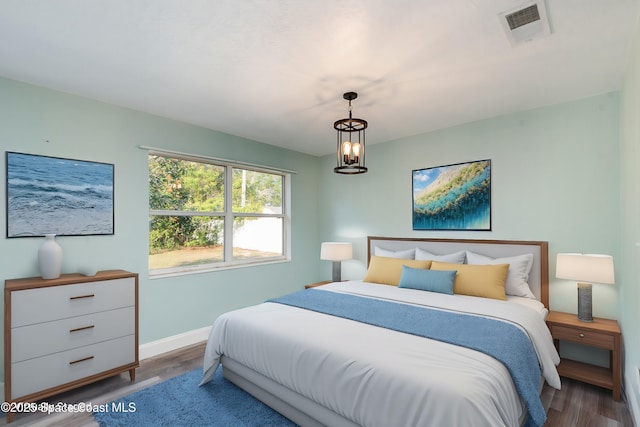 bedroom with dark hardwood / wood-style flooring and a chandelier