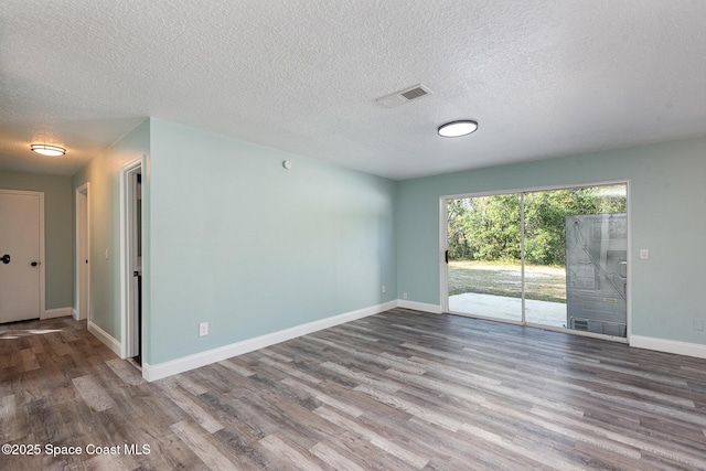 unfurnished room featuring wood-type flooring and a textured ceiling