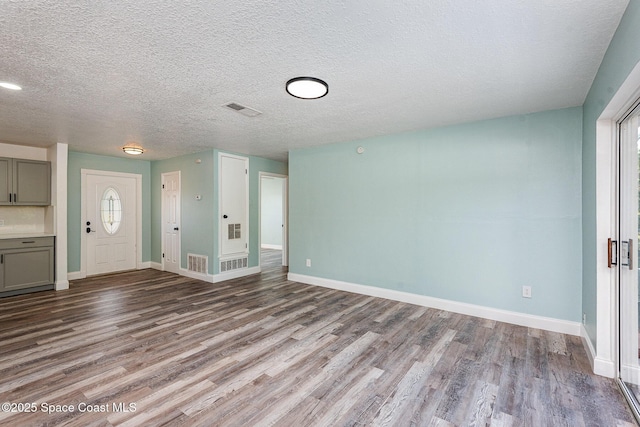 unfurnished living room with light hardwood / wood-style floors and a textured ceiling