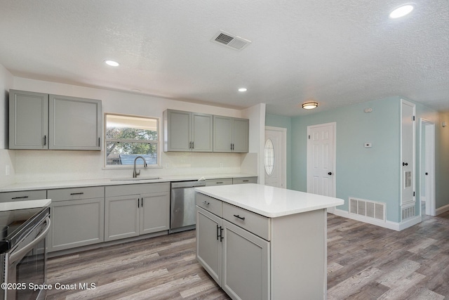 kitchen with gray cabinetry, sink, a kitchen island, and appliances with stainless steel finishes