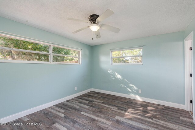 empty room with ceiling fan, a textured ceiling, dark hardwood / wood-style floors, and a healthy amount of sunlight