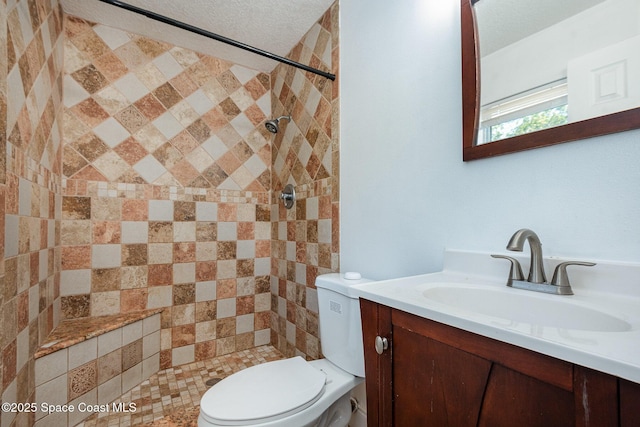 bathroom with a tile shower, vanity, and toilet