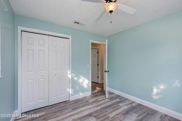 unfurnished bedroom featuring a textured ceiling, light wood-type flooring, and a closet