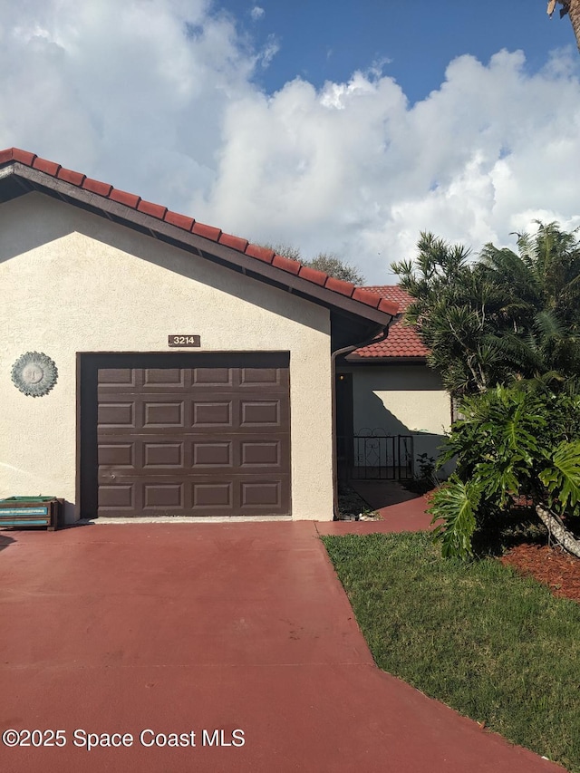 view of front facade with a garage, a tiled roof, concrete driveway, and stucco siding