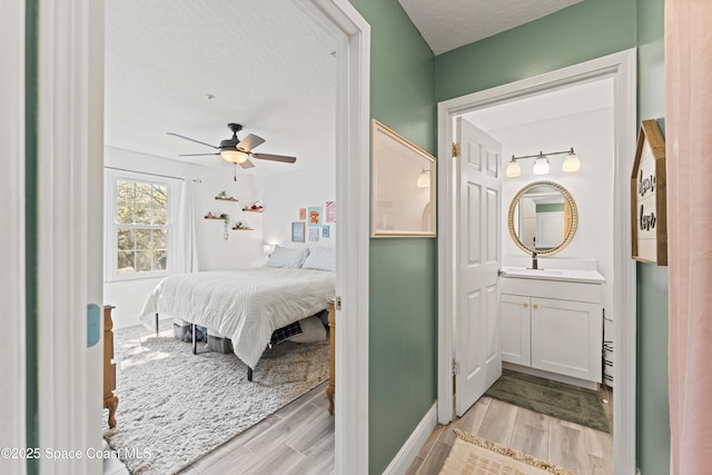 bedroom with ceiling fan, a textured ceiling, and light hardwood / wood-style flooring