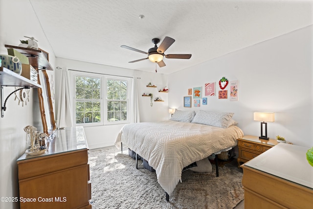 carpeted bedroom with ceiling fan and a textured ceiling