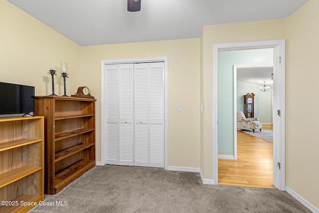 bedroom with ceiling fan, light colored carpet, a closet, and a textured ceiling