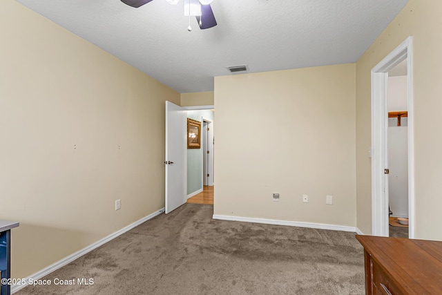 unfurnished bedroom with ceiling fan, carpet floors, and a textured ceiling