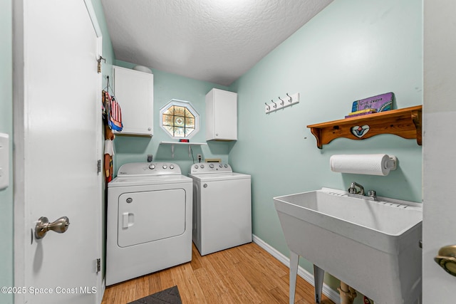 washroom with washer and dryer, sink, cabinets, light hardwood / wood-style floors, and a textured ceiling