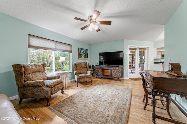 living room with a textured ceiling, light hardwood / wood-style flooring, and ceiling fan