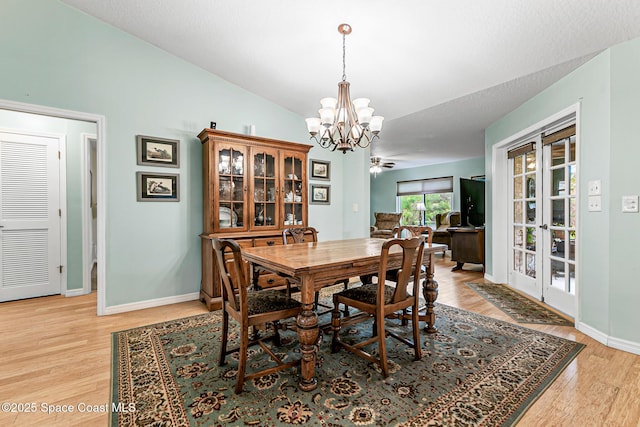 dining room with vaulted ceiling, light hardwood / wood-style floors, and a chandelier