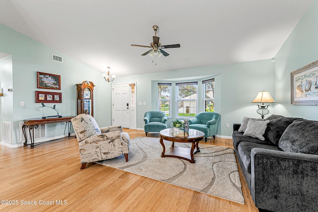 living room featuring hardwood / wood-style flooring, lofted ceiling, and ceiling fan with notable chandelier