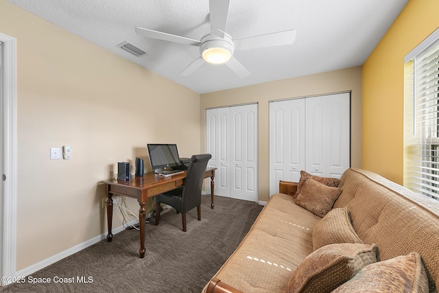 office area with ceiling fan, a textured ceiling, and dark carpet